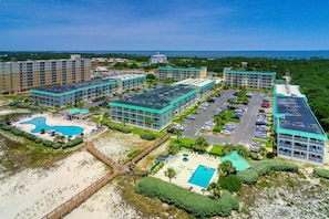 A resort with multiple buildings, a swimming pool, and a beach area. - Beachfront condo with private balcony, pools, tennis, gyms, & saunas (Gulf Shores)