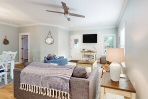 Ein Wohnzimmer mit Deckenventilator, Fernseher, Sofa, Couchtisch und Lampe.