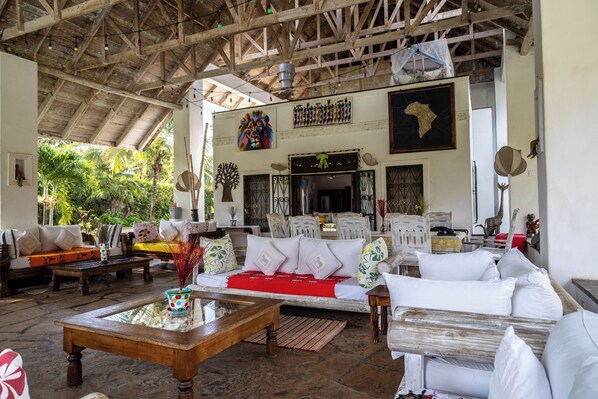 A spacious living area with a high ceiling, wooden beams, and a variety of seating options including sofas and chairs.