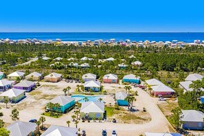 A coastal residential area with houses, a swimming pool, and a view of the ocean. - Modern beach home with screened porch, on-site pool, AC, & W&D (Gulf Shores)