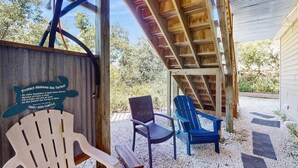 A wooden structure with a sign about protecting Alabama sea turtles, a chair, a blue Adirondack chair, and a wooden bench. - Downstairs duplex near the beach with full kitchen, WiFi, cable, partial AC (Gulf Shores)