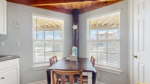 A dining area with a wooden table and chairs, two windows with blinds, a white door, and a kitchen counter. - Downstairs duplex near the beach with full kitchen, WiFi, cable, partial AC (Gulf Shores)