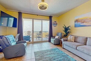 Ein Wohnzimmer mit Sofa, Sessel und einem an der Wand befestigten Fernseher.