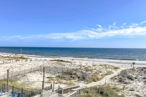 Ein Strand mit einer Holzzahlung, einem hölzernen Steg und wolkenlosem, blauem Himmel.