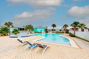 A swimming pool with lounge chairs, a blue building, and palm trees. - Brand-new cottage with covered patio, central AC, W&D, & pool access - near beach (Gulf Shores)