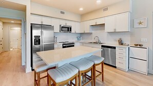 Una cocina moderna con una isla central, electrodomésticos de acero inoxidable y armarios blancos.