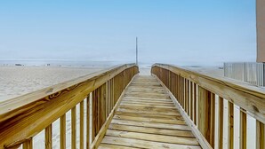 Un paseo marítimo de madera que conduce a una playa bajo un cielo despejado.