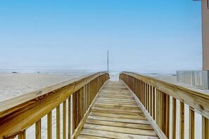 A wooden boardwalk leading to a beach with a clear sky. - Brand-new beach condo with pool, hot tub, AC & washer/dryer (Gulf Shores)