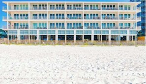 A multi-story hotel with balconies on each floor, located on a sandy beach. - Brand-new beach condo with pool, hot tub, AC & washer/dryer (Gulf Shores)