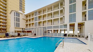 Un hotel con piscina, varios balcones y un diseño arquitectónico moderno.