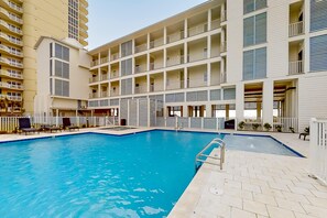 A hotel with a swimming pool, multiple balconies, and a modern architectural design. - Brand-new beach condo with pool, hot tub, AC & washer/dryer (Gulf Shores)