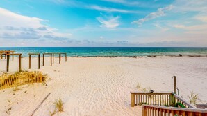 Una playa con estructuras de madera, una orilla arenosa y un cielo azul despejado.