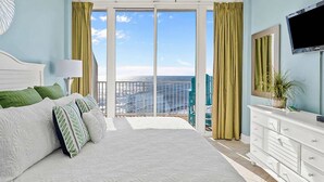 Ein Schlafzimmer mit einem großen Bett, einem Schminktisch, einem Fernseher und einem Balkon mit Blick.