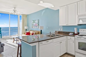 A kitchen with a large island, white cabinets, a stove, and a view of the ocean. - Beachfront Condo w Great Gulf View, Balcony, WiFi, Shared Pools, Hot Tub & Saunas (Gulf Shores)