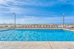 A swimming pool with lounge chairs and a view of the beach. - 5th-Floor Beach View Condo w/Balcony, Shared Pool, Outdoor Shower, A/C, WiFi (Gulf Shores)