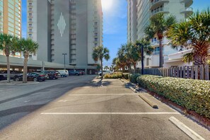 A parking lot with cars, palm trees, and tall buildings in the background. - Family-friendly Gulf-front condo with private balcony, hot tub, pool, & gym (Gulf Shores)
