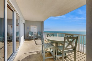 A balcony with a table and chairs, a view of the ocean, and a door leading to another room. - Family-friendly Gulf-front condo with private balcony, hot tub, pool, & gym (Gulf Shores)