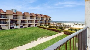 Un hotel con varios balcones, césped y vista a la playa.