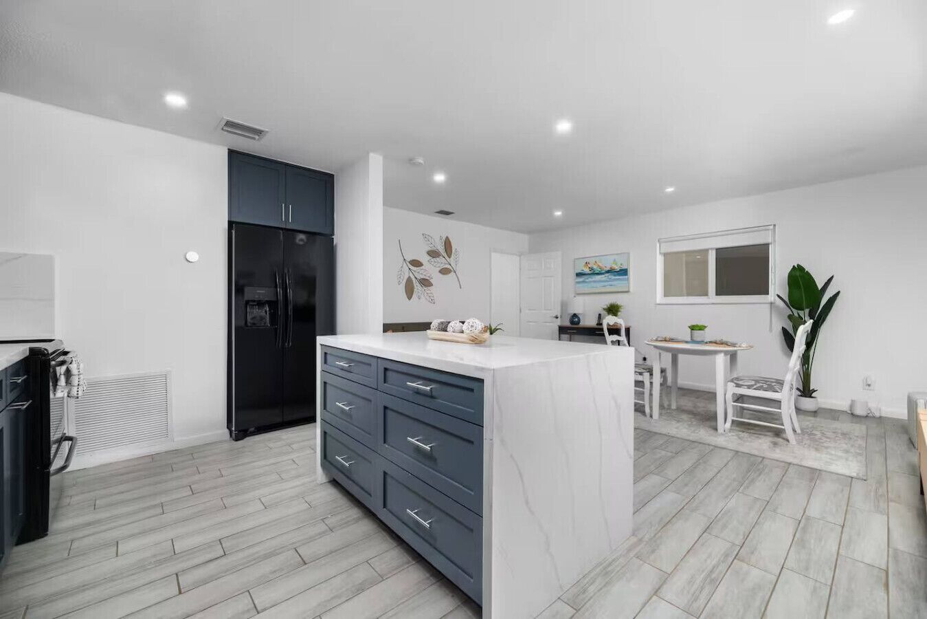 A modern kitchen with a marble island, dark cabinets, and a built-in refrigerator.