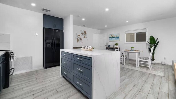 A modern kitchen with a marble island, dark cabinets, and a built-in refrigerator. - Your Downtown Getaway 2 (Fort Lauderdale)
