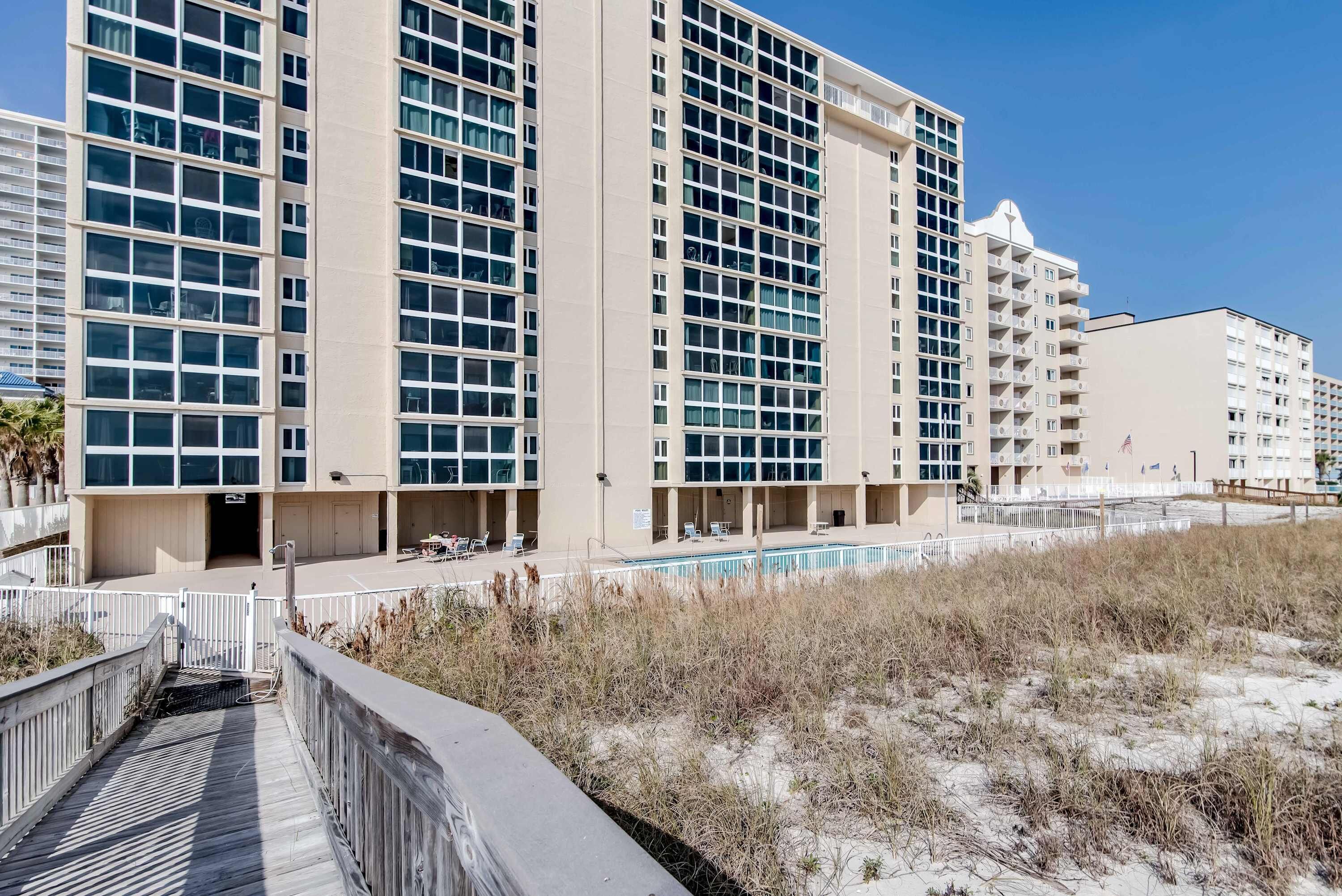 A multi-story hotel with a pool, beach access, and a boardwalk.