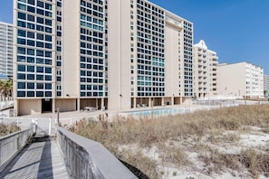 A multi-story hotel with a pool, beach access, and a boardwalk. - Beachfront condo with enclosed balcony, pool, views, central AC, & grill (Gulf Shores)