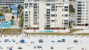 Un hôtel à étages, doté d’une piscine et d’un espace de plage aménagé avec des parasols.