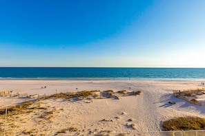 A beach with a clear sky, sandy shore, and a few structures along the edge. - Gulf-front 5th-floor condo with balcony, pool & beach access - snowbird-friendly (Gulf Shores)