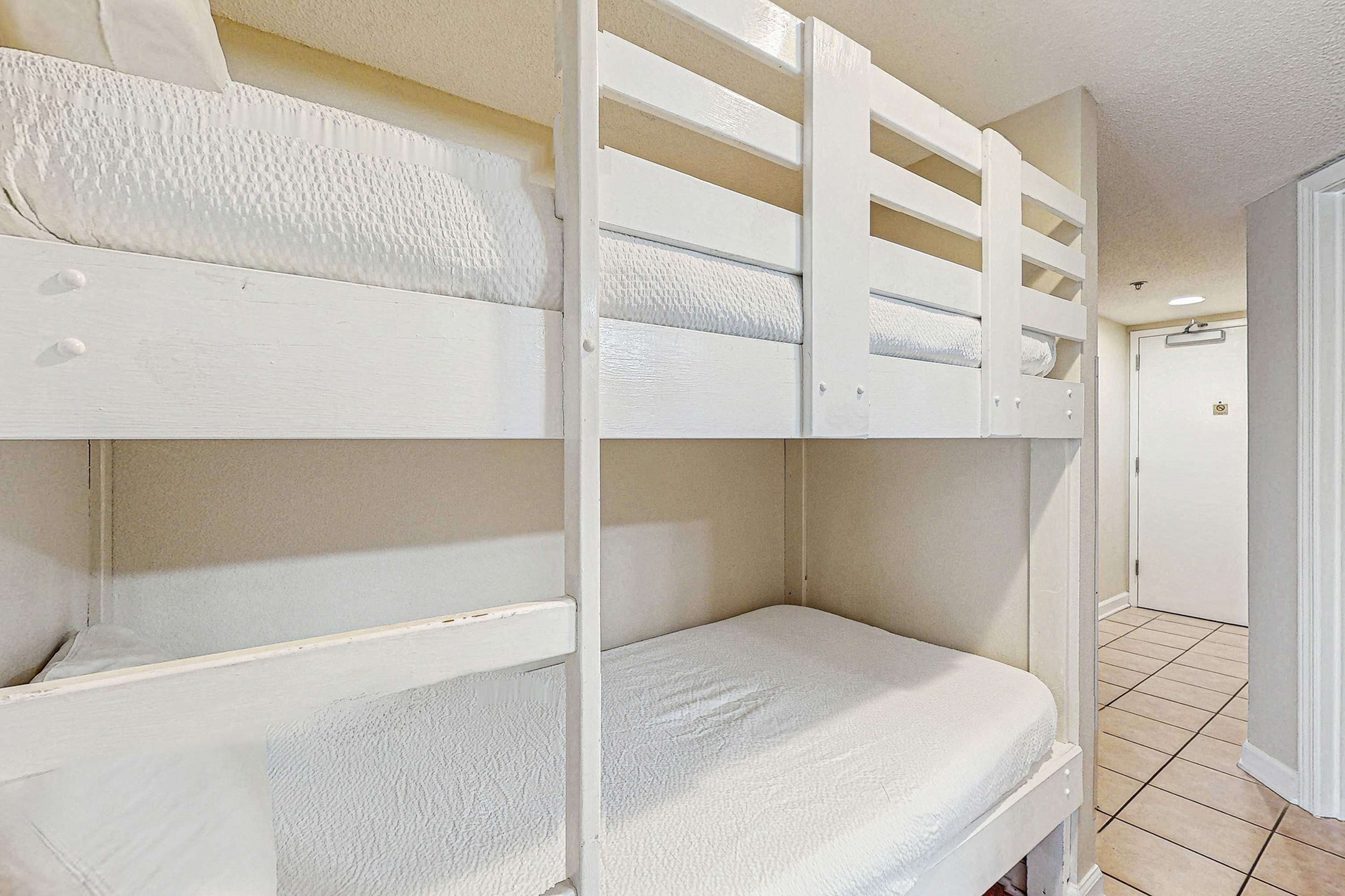 Ein Schlafraum mit Etagenbetten, einer Tür und einem gefliesten Boden.