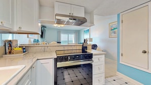 A kitchen with white cabinets, a stainless steel range hood, a built-in oven, and a tiled floor. - Gulf-front 3rd-floor condo with outdoor pool, central AC, & balcony (Gulf Shores)