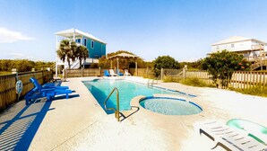 Ein Pool mit Liegestühlen, einem Whirlpool und einem Haus im Hintergrund.