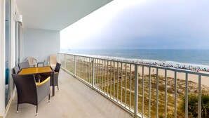 A balcony with a view of the beach, wicker furniture, and a railing. - Gulf-Front Condo w Shaded Balcony, WiFi, AC & Shared Pools, Hot Tubs & Sauna (Gulf Shores)