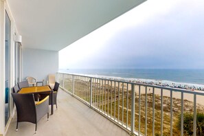 Ein Balkon mit Blick auf den Strand, Korbmöbel und Geländer.