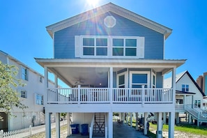 A two-story house with a balcony, a covered porch, and a small outdoor seating area. - Waterview getaway with Private Pier, Balcony and Kayaks (Gulf Shores)