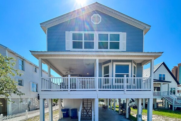 A two-story house with a balcony, a covered porch, and a small outdoor seating area. - Waterview getaway with Private Pier, Balcony and Kayaks (Gulf Shores)