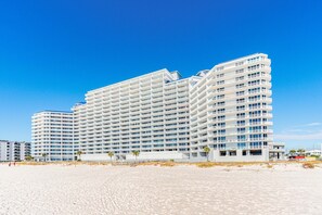 A multi-story hotel with a modern design, featuring balconies and a beach view. - Bright beachfront condo w private balcony, zero-entry pool, gym, & hot tub (Gulf Shores)