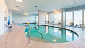 Une piscine intérieure au design incurvé, entourée de chaises longues et offrant une vue sur la ville.