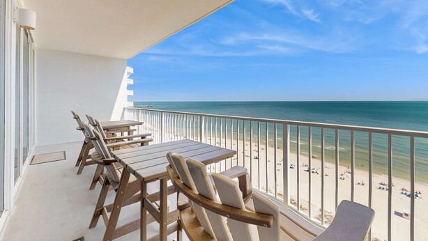 Un balcon avec vue sur la plage, une table et des chaises.