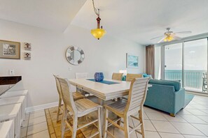 Un espace repas comprenant une table, des chaises, un ventilateur de plafond et une grande fenêtre donnant sur un beau paysage.