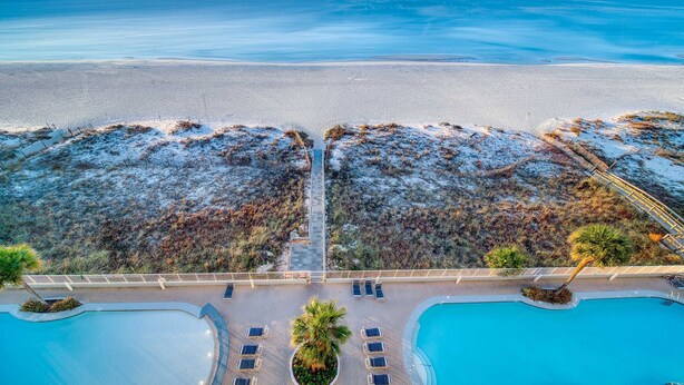 Un resort con piscina, sillas de descanso y vistas a la playa y el océano.