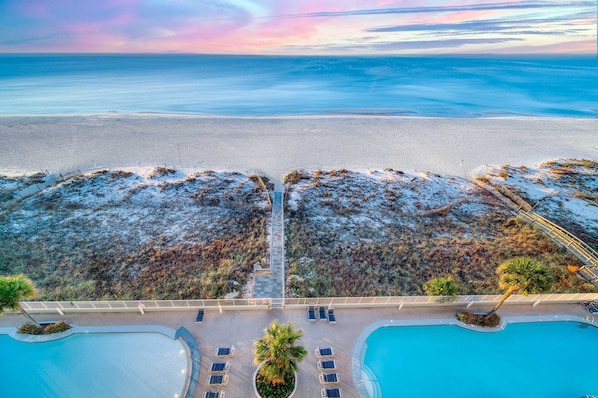 Ein Resort mit Pool, Liegestühlen und Blick auf Strand und Meer.