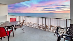 Un balcón con vistas al mar, una mesa y sillas.
