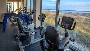 Un gimnasio con máquinas de cardio y vista al mar.
