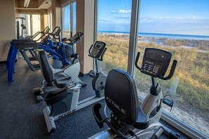 Ein Fitnessraum mit Cardiogeräten und Blick auf den Strand.