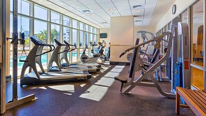 Ein Fitnessraum mit Laufbändern, Kraftgeräten und einer Bank.