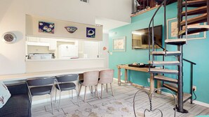 A modern kitchen with a built-in oven, a dining area with chairs, and a spiral staircase. - Beachfront condo with outdoor pool, beach views, washer/dryer, beach access (Gulf Shores)
