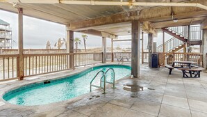 An indoor swimming pool with a concrete floor, metal railings, and a view of the beach. - Beachfront condo with outdoor pool, beach views, washer/dryer, beach access (Gulf Shores)