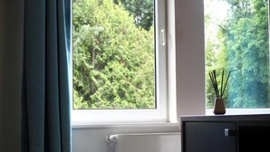 A room with a window, a radiator, and a small cabinet with a decorative item on top. - Koblenz Valley Hotel by Belvilla Double Room (Bendorf)