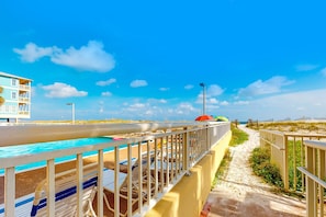 A beachside walkway with a pool, beach chairs, and a building in the background. - Beach/Gulf-front condo with water views, on-site pool, & private balcony (Gulf Shores)