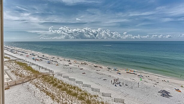 Une plage avec une promenade en bois, des parasols et un ciel dégagé.